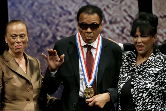 Retired boxing champion Muhammad Ali (center) waves alongside his wife Lonnie Ali (left) and his sister-in-law Marilyn Williams after receiving the Liberty Medal during a ceremony at the National Constitution Center in Philadelphia on Thursday. ( AP-Yonhap News)