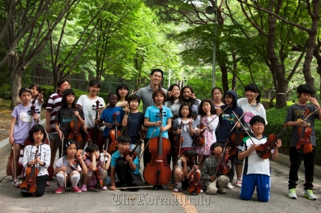 Violist Richard Yongjae O’Neill (center, back row) poses with the children appearing in “Hello?! Orchestra.” (CREDIA)