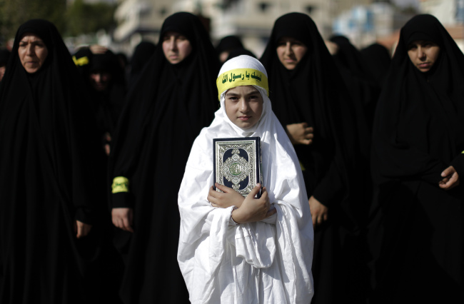 A Lebanese girl holds a copy of the Quran, the Muslim holy book, during a protest about a film ridiculing Islam’s Prophet Muhammad in the southern border town of Bint Jbeil, Lebanon, Saturday, for the latest in a series of protest rallies organized by the Shiite militant group Hezbollah. Arabic writing on her headband reads “at your service God’s Prophet.” ( AP-Yonhap News)