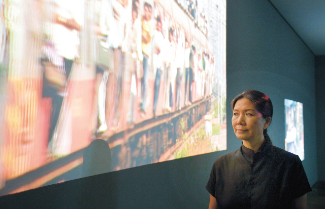 Artist Kim Sooja stands in front of “Mumbai: A Laundry Field,” a four-channel video projection, on Sept. 12 at Kukje Gallery in Seoul. (Kim Myung-sub/The Korea Herald)