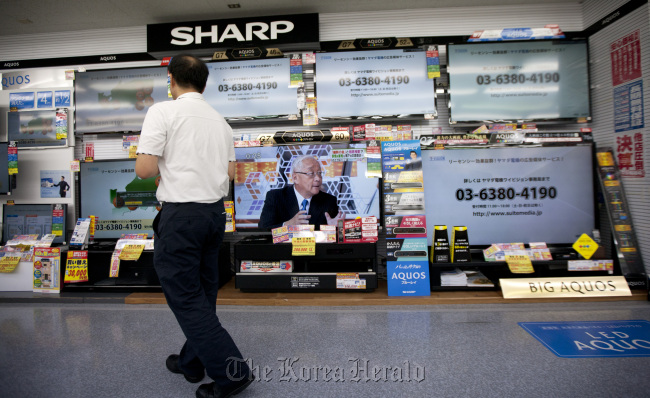 A customer looks at Sharp Corp. liquid crystal display television sets at an electronics store in Tokyo. (Bloomberg)