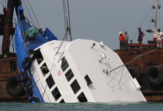 Officials check on a half submerged boat after it collided Monday night near Lamma Island, off the southwestern coast of Hong Kong Island Tuesday Oct. 2, 2012. (AP-Yonhap News)