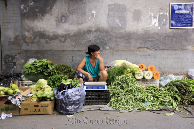 A vegetable vendor waits for customers in a hutong, Beijing. (Bloomberg)