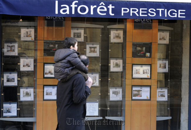 A pedestrian passes real estate agent’s window advertising property for sale in the 6th arrondissement district of Paris. (Bloomberg)