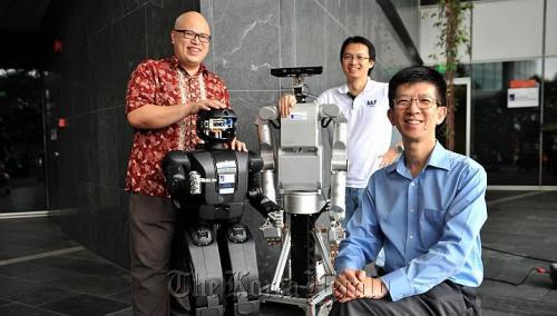 Scientists making better robots include (from left) Han Boon Siew with his black robot Hubo, Tee Keng Peng with his Meka Robot, and Li Haizhou, the department head and principal scientist of the Human Language Technology Department, at A*Star’s Institute for Infocomm Research. (The Straits Times)