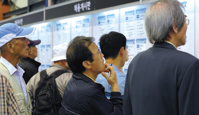 Job seekers look through openings at a job fair for over-55s in Seoul on Sept. 25. (Yonhap News)