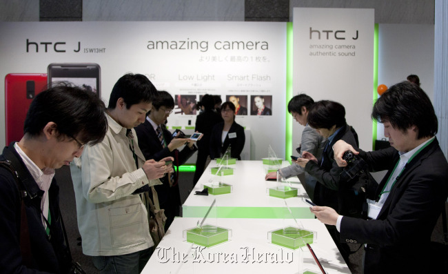 Members of the media try HTC J smartphones at its unveiling held by HTC Corp. and KDDI Corp. in Tokyo. (Bloomberg)