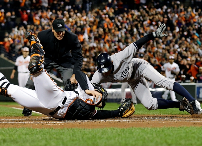 New York Yankees` Ichiro Suzuki (right) leaps past Baltimore Orioles catcher Matt Wieters to score a run on a double by Robinson Cano during Game 2 of the American League division baseball series on Monday in Baltimore. (AP-Yonhap News)