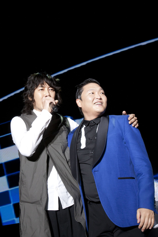 Entertainers Kim Jang-hoon (left) and Psy publicly rekindle their friendship at the “Night of the Stars 2012” concert on Wednesday after a recent plagiarism dispute between the two. (Yonhap News)