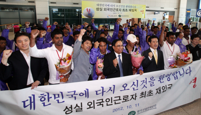 Foreign workers with re-employment permits and Seoul officials pose during a welcoming ceremony at Incheon International Airport on Thursday. (Yonhap News)