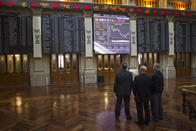 Visitors look at screens inside the Madrid Stock Exchange. (Bloomberg)