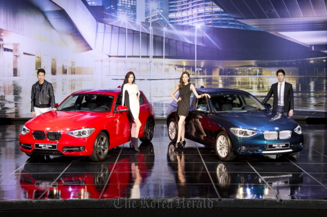 Models pose with BMW’s new 1 Series hatchback at a launching event held in Seoul on Thursday. (BMW Korea)