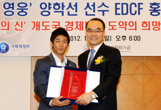 Strategy and Finance Minister Bahk Jae-wan (right) poses with Olympic gold medalist Yang Hak-seon after appointing him as a goodwill ambassador for the Economic Development Cooperation Fund, at Lotte Hotel, downtown Seoul, Sunday. (Yonhap News)