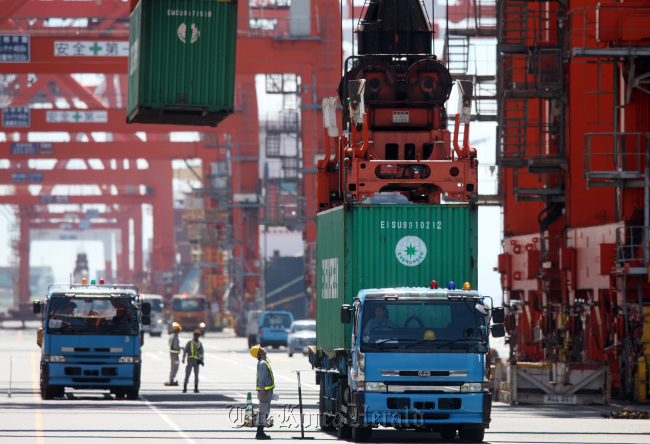 Workers look at an Evergreen Marine Corp. container being loaded at a shipping terminal in Tokyo. (Bloomberg)