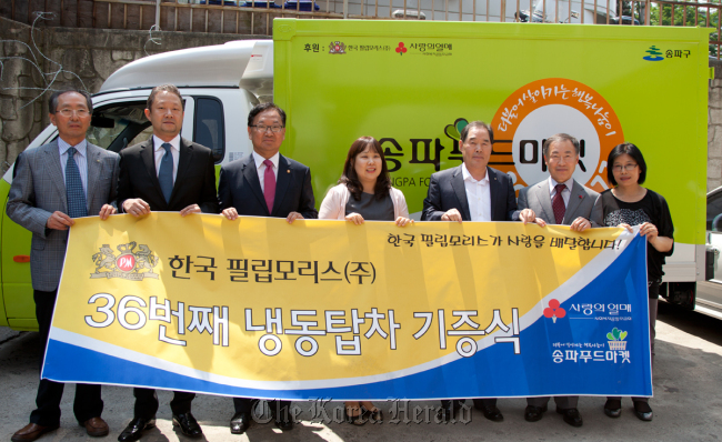 Philip Morris Korea President Chong Il-woo (second from left) poses with a placard showing the firm’s donation of a refrigerated food truck to Songpa Food Market at a ceremony in May. (Korea Herald file photo)