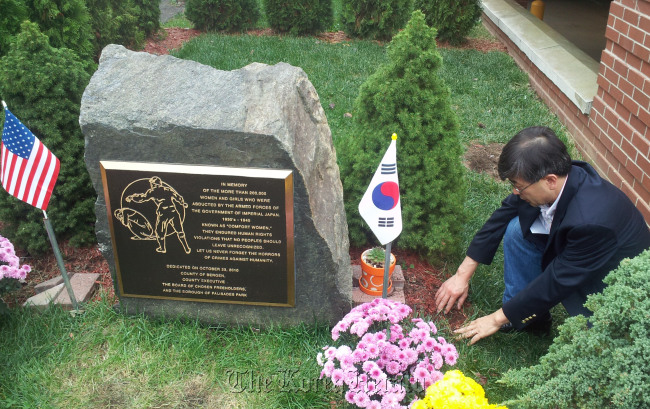 An official with the Korean American Civic Empowerment, a U.S.-based civic group, points at where a wooden post was found Friday beside a monument at a public park in New Jersey that commemorates Korean women forced into sexual slavery by Japanese troops during World War II. (Yonhap News)