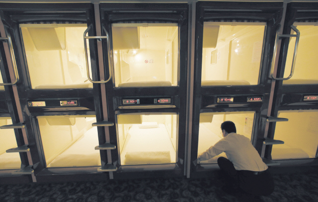 Manager Akiyoshi Kaneko stands by the rooms at the Capsule & Sauna Century Shibuya in Tokyo on Oct. 29. (AP-Yonhap News)