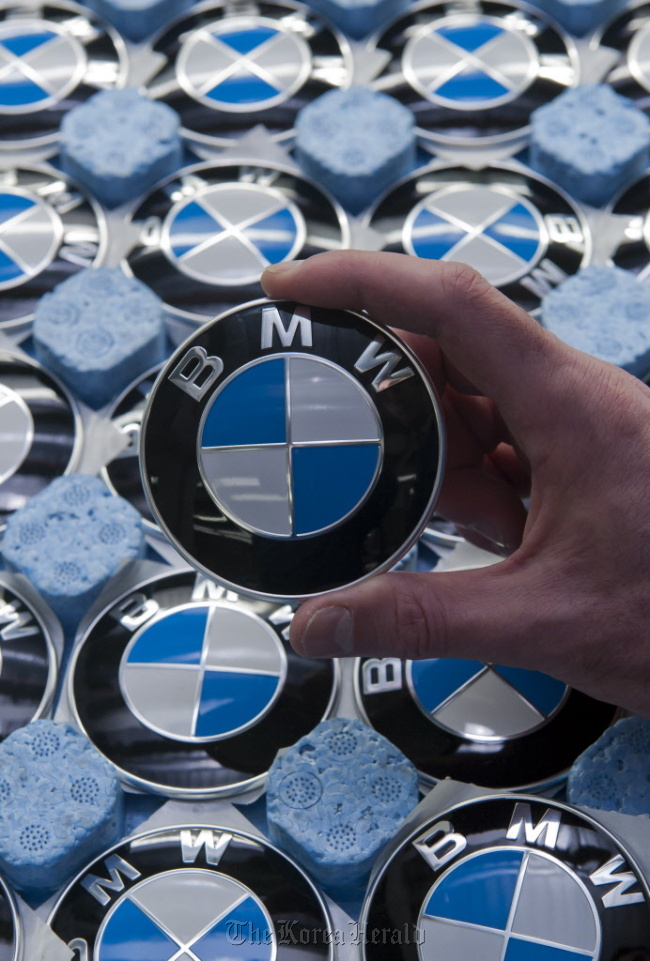 An employee holds a BMW badge at the company‘s assembly plant in Regensburg, Germany. (Bloomberg)