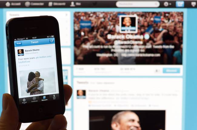 A person poses with a cell phone in front of a computer screen to check Barack Obama's tweet on November 7, 2012 in Paris after his re-election as US president. Barack Obama brought his sophisticated social media campaign to an emotional climax, proclaiming his victory on Twitter and Facebook just as TV networks were breaking the news. The post was his most re-tweeted -- 472,000 shares in three hours -- according to Twitter's politics account @gov. It was also the most popular ever, topping a message from singer Justin Bieber, website BuzzFeed said. (AFP-Yonhap News)