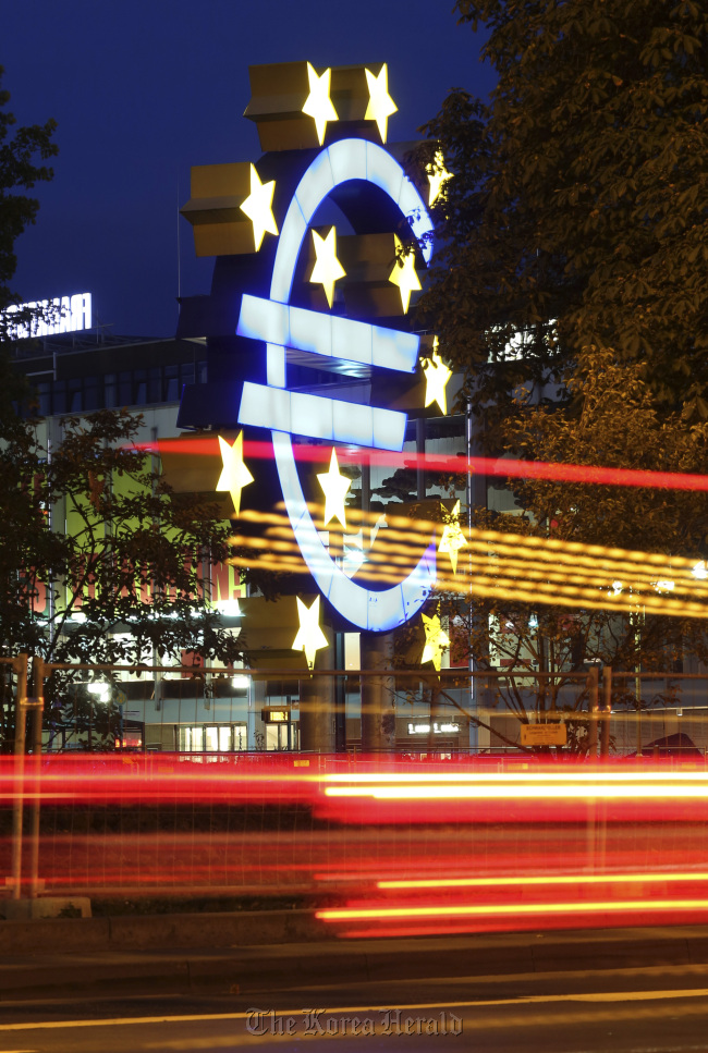 Light trails from passing automobiles are seen in front of the euro sign sculpture outside the headquarters of the European Central Bank in Frankfurt. (Bloomberg)