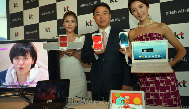 KT president Pyo Hyun-myung (center), along with models, holds out a smartphone operated by Olleh ALL-IP, the firm’s new data-sharing service for multiple-device users, at a press conference held in KT Seoul headquarters, Tuesday. (Kim Myung-sub/The Korea Herald)