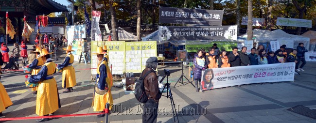 Labor unionists protest in front of Deoksu Palace in central Seoul on Thursday while a traditional court ritual is reenacted. (Kim Myung-sub/The Korea Herald)