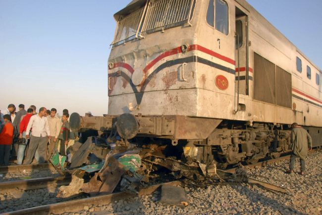 Egyptians gather at the site of a train crash that killed at least 51 people near Assiut in southern Egypt on Saturday. (AP-Yonhap News)