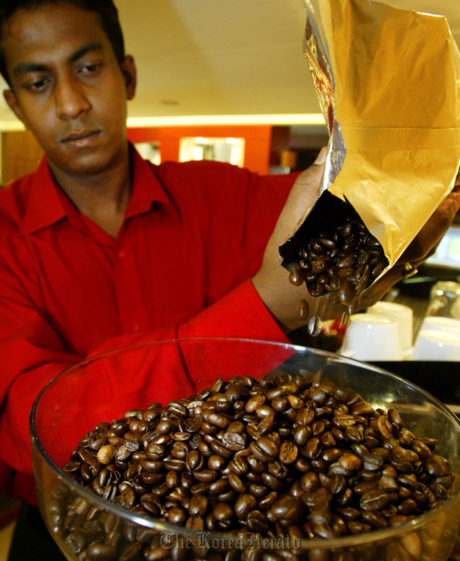 A cafe employee pours coffee beans into a grinder at a Cafe Coffee Day outlet in New Delhi, India. (Bloomberg)