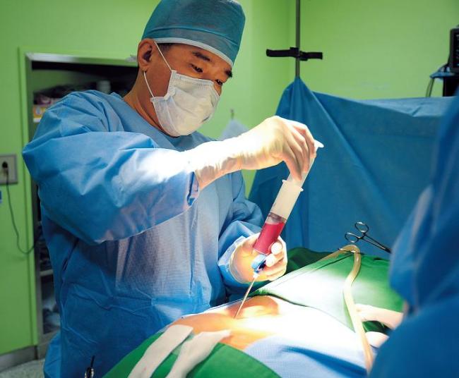 A surgeon performs spinal surgery on a patient at a hospital in Incheon. Recent moves by the Ministry of Health to allow for-profit hospitals have spurred concerns about the impact on the public health system. (Yonhap News)