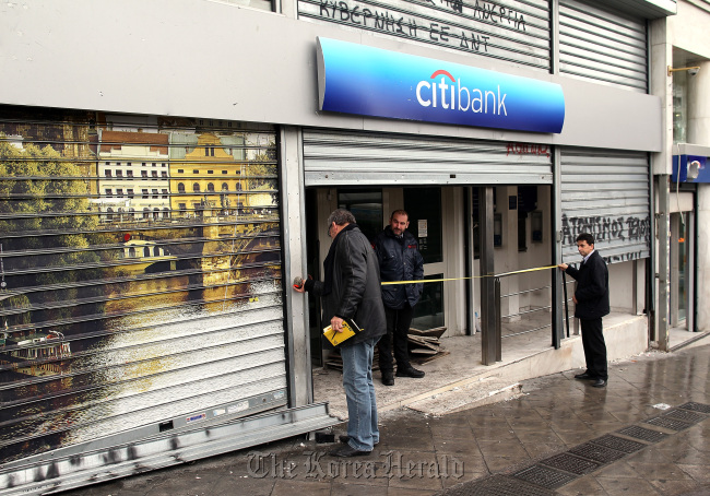 A man measures the metal shutters at the entrance to a Citigroup Inc. Citibank branch in Athens. (Bloomberg)