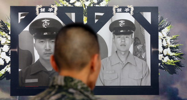 A soldier looks at pictures of soldiers killed during North Korea’s artillery attack on Yeonpyeongdo on Nov. 23, 2010, in an exhibition to mark its second anniversary, at Gimpo Airport, Tuesday. (Yonhap News)