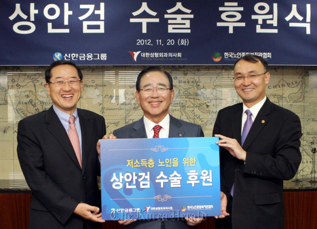 Shinhan Financial Group chairman Han Dong-woo (center) attends a ceremony to mark the lender’s support for elderly people’s eyelid surgery on Tuesday. (Shinhan Financial Group)