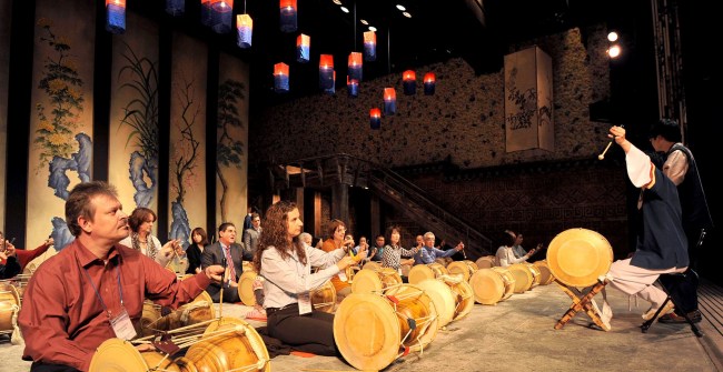 Participants of Invest Korea’s “Get to Know Korea” event learn how to play janggu at Chongdong Theater in central Seoul on Saturday. (KOTRA)