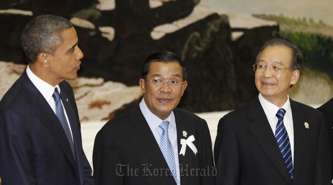 U.S. President Barack Obama (left) chats with China's premier Wen Jiabao (right) as Cambodia's prime minister Hun Sen stands between them during a photo session at the East Asia Summit in Phnom Penh on Nov. 20. (AP-Yonhap News)