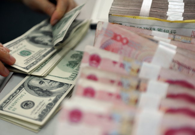 A worker counts U.S. dollars at a bank in Qionghai City, Hainan province, China. (Xinhua-Yonhap News)