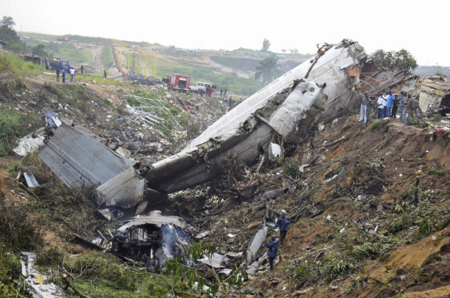 Rescue workers walk among the crash site of a cargo airplane near the airport at Brazzaville, Republic of Congo, Saturday. (AP-Yonhap News)