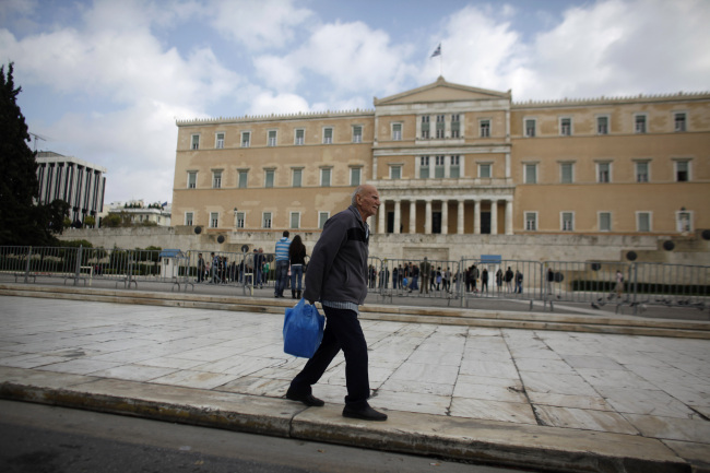 A pedestrian carries his shopping bag past the Greek parliament on Syntagma square in Athens. (Bloomberg)