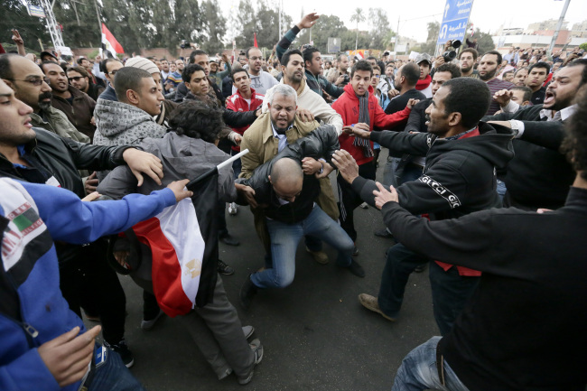 Egyptian President Mohammed Morsi’s supporters beat an opponent (center) during clashes outside the presidential palace in Cairo on Wednesday. (AP-Yonhap News)