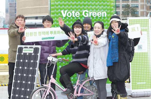 Activists of Greenpeace Korea pose for photos Wednesday in front of a monument erected in front of Seoul City Hall, as part of its campaign to urge voters to examine the environmental visions of the presidential candidates. (Yonhap News)