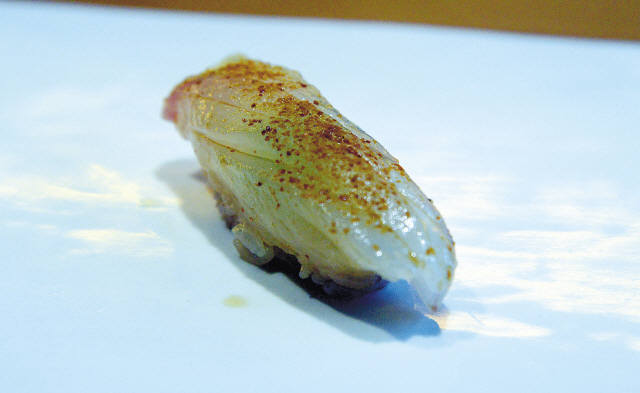 Umami-tasting uni salt made from dried, grated sea urchin is sprinkled over hirame (halibut).