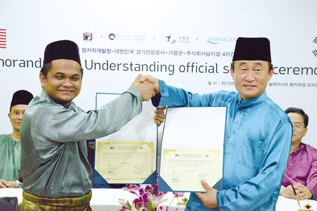 Representatives of Langkawi Development Authority and Nami Island Inc. shake hands at a memorandum of understanding signing held at the Malaysian island earlier this month. (Yonhap News)