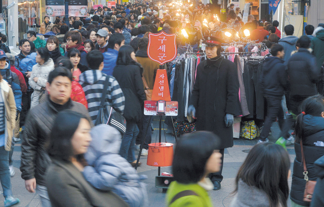 Pedestrians pass by the red kettle of the Korean Salvation Army in Myeong-dong, downtown Seoul, on Dec. 2. (Lee Sang-sub/The Korea Herald)