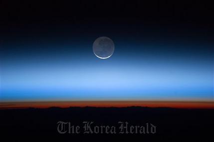 This undated image made available by NASA and photographed by the Expedition 28 crew aboard the International Space Station, shows the moon, at center with the limb of Earth near the bottom transitioning into the orange-colored troposphere, the lowest and most dense portion of the Earth’s atmosphere. A team of former NASA executives are launching a private venture to send people to the moon for $1.5 billion. The newly formed business is offering countries a two-person trip to the moon, either for research or national prestige. (AP Photo/NASA)