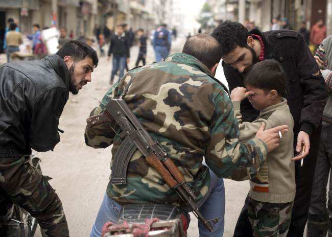 Seven-year-old Walid (right) is comforted as he mourns a fallen Syrian rebel fighter taken away for burial in the al-Fardos area of Aleppo on Saturday. (AFP-Yonhap News)