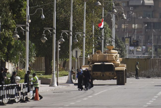 Egyptian women walk in front of an armored personnel carrier deployed near the presidential palace in Cairo on Monday. (AFP-Yonhap News)