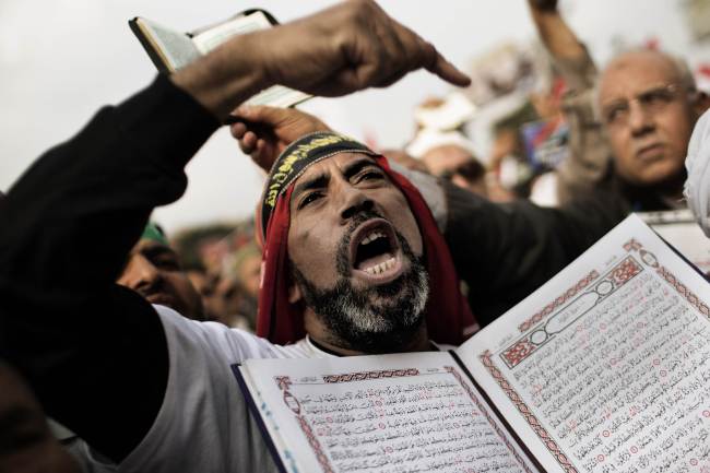 A supporter of Egypt's President Mohamed Morsi and the Muslim Brotherhood holds a copy of the Koran, Islam's holy book, as he shouts slogans during a demonstration in Cairo's Nasr City on Friday. (AFP-Yonhap News)