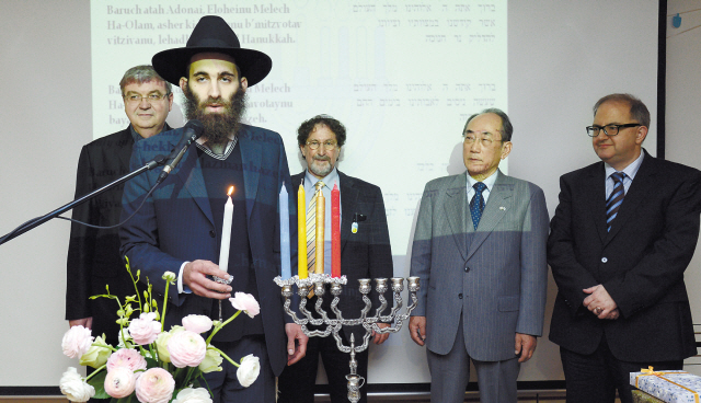 Rabbi Osher Litzman (second from left) of Chabad Jewish Community of Korea prepares to light the menorah candles on the fourth day of Hanukkah as Israeli Ambassador to Korea Tuvia Israeli (left) looks on at the Israeli Culture Center in southern Seoul, Tuesday. (Ahn Hoon/The Korea Herald)