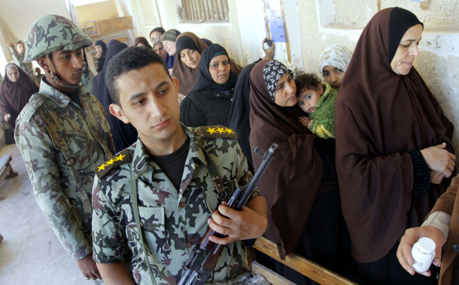 An Egyptian army officer stands near women as they prepare to vote for the second round of a referendum on a disputed constitution drafted by Islamist supporters of President Mohammed Morsi in Giza, Egypt on Saturday. (AP-Yonhap News)