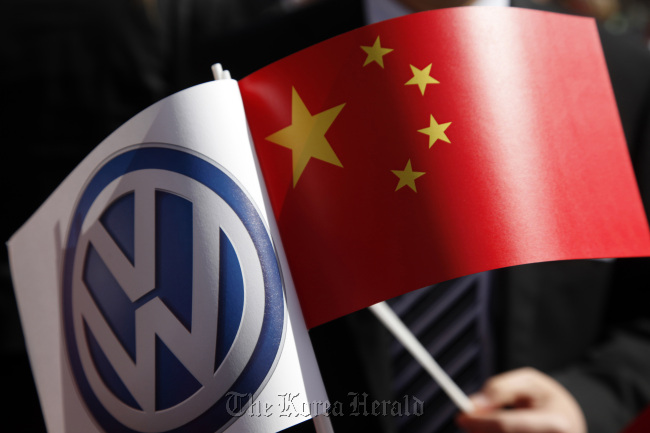 A man holds a Volkswagen AG flag (left) alongside the Chinese national flag during the German-Chinese signing ceremony at Volkswagen AG’s headquarters. (Bloomberg)