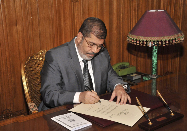 Egypt’s President Mohammed Morsi signs into law the country’s Islamist-backed constitution. (AP-Yonhap News)